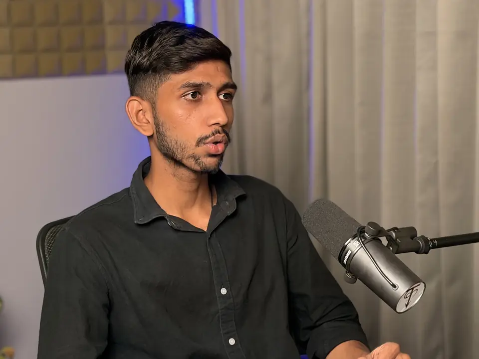 Host speaking into a broadcast microphone against a dark curtain