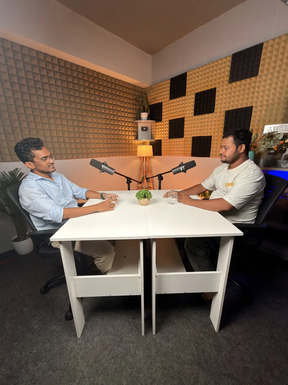 Wide view of a two-person podcast at a white table
