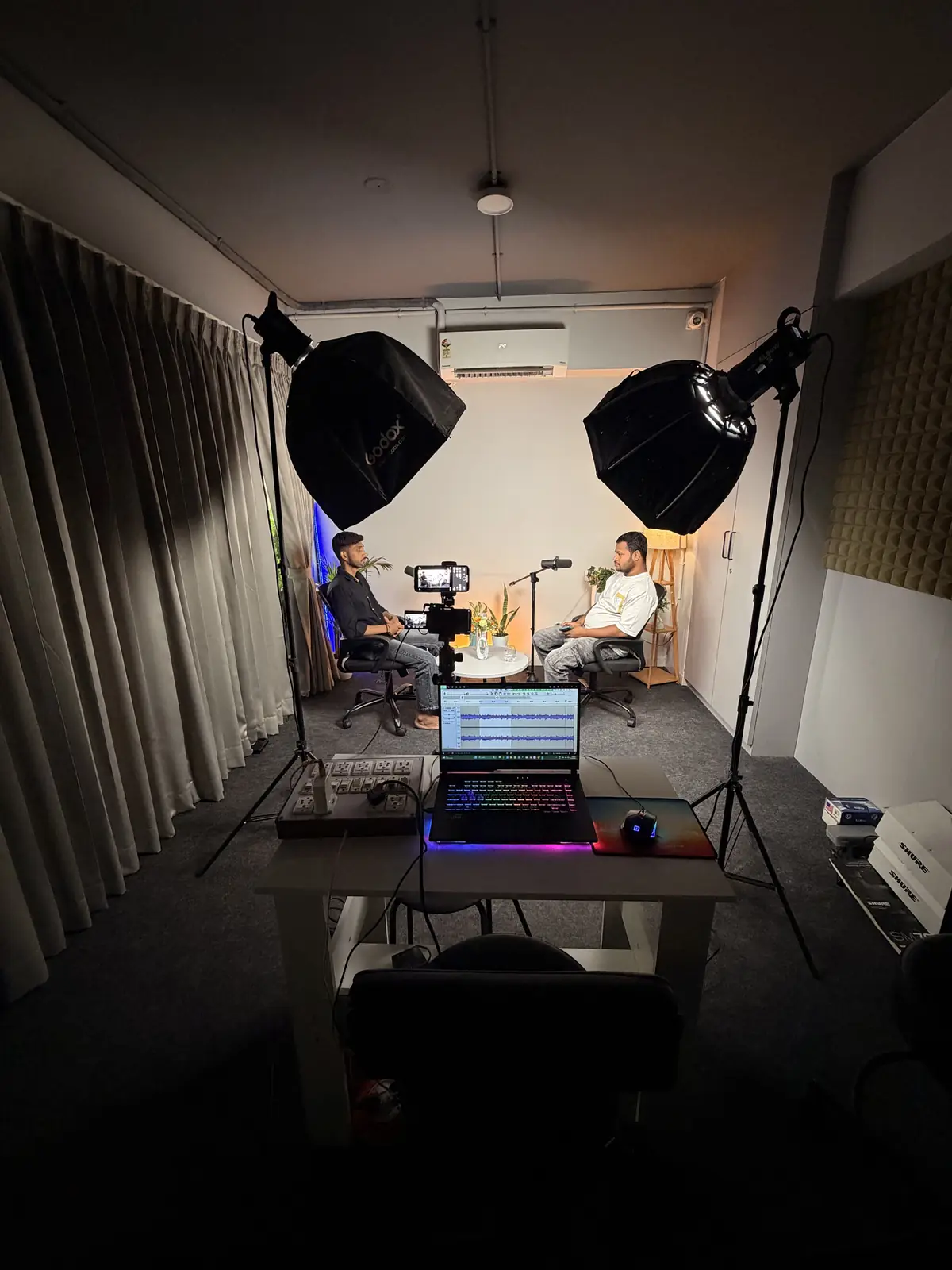 Editing laptop on a studio desk with softboxes behind
