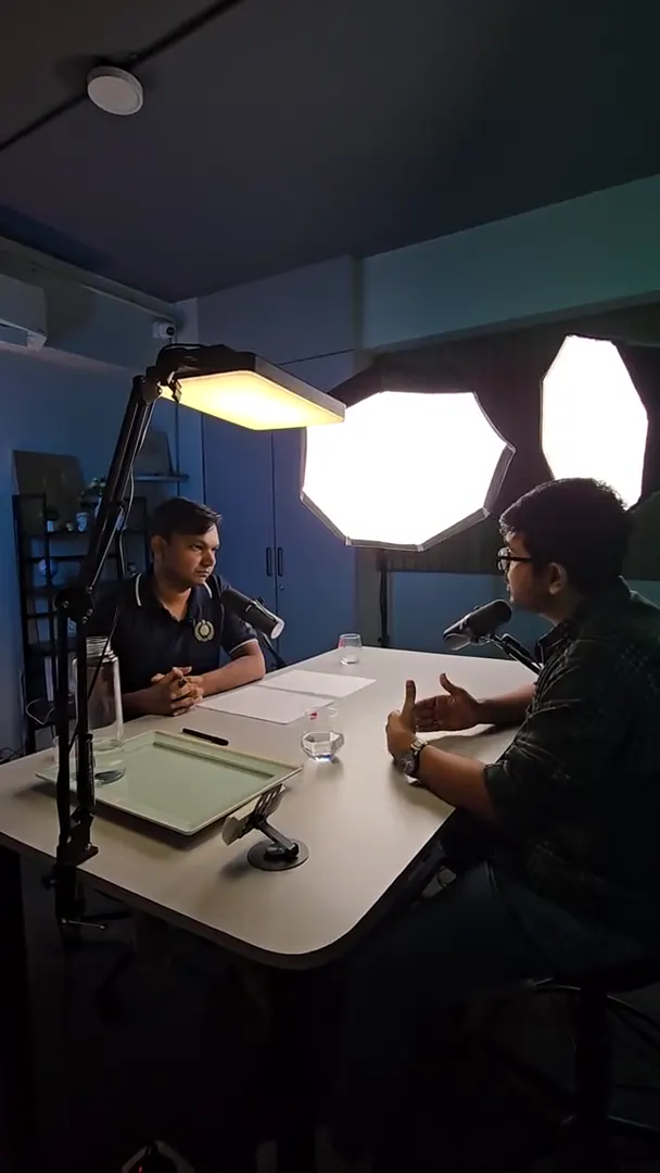 Two people recording at a table under softboxes in a blue-lit room